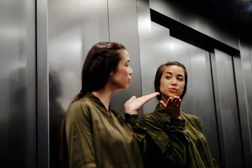 Kobieta przesyłająca buziaka do swojego odbicia w lustrze